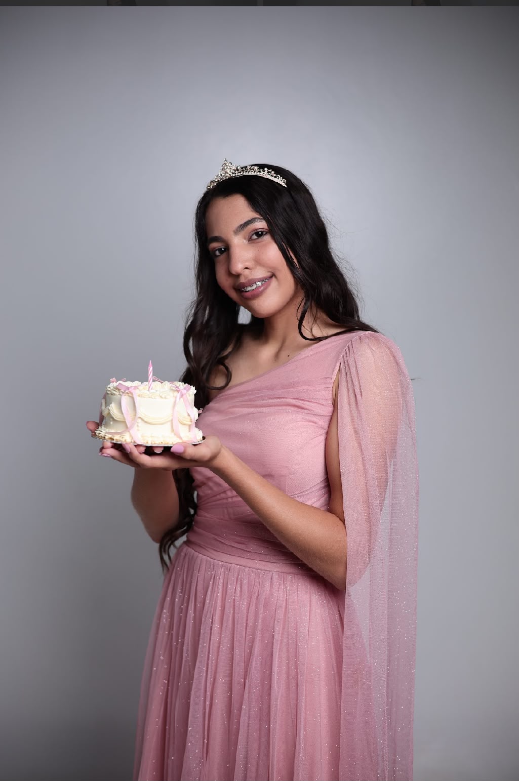 Ana Laura, com vestido rosa e tiara, segurando um bolo de aniversário